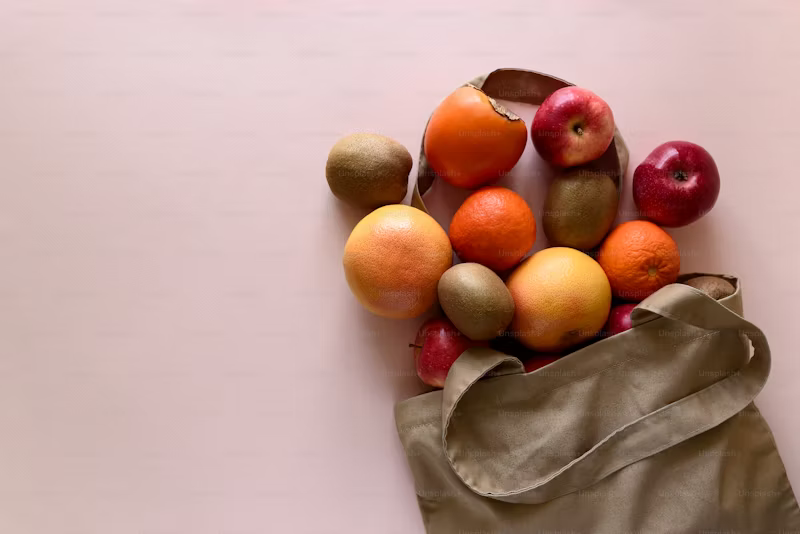 apples, keiwi and oranges spilling from bag onto counter