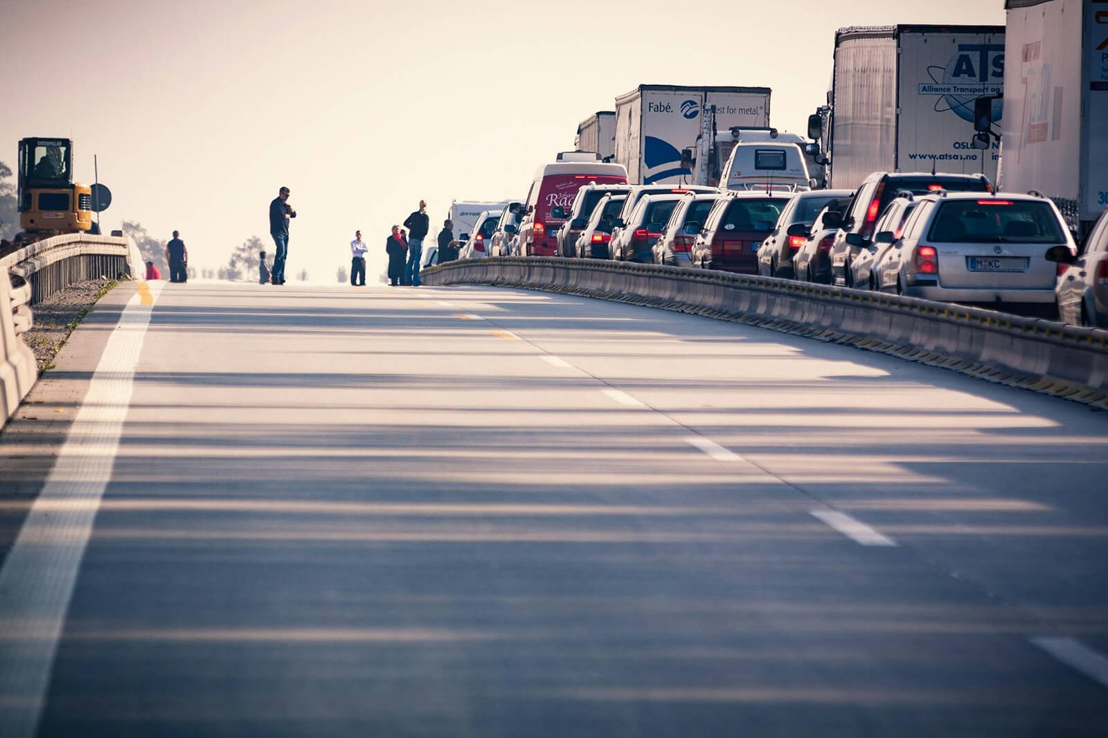 vehicles in traffic and people walking on closed road next to traffic