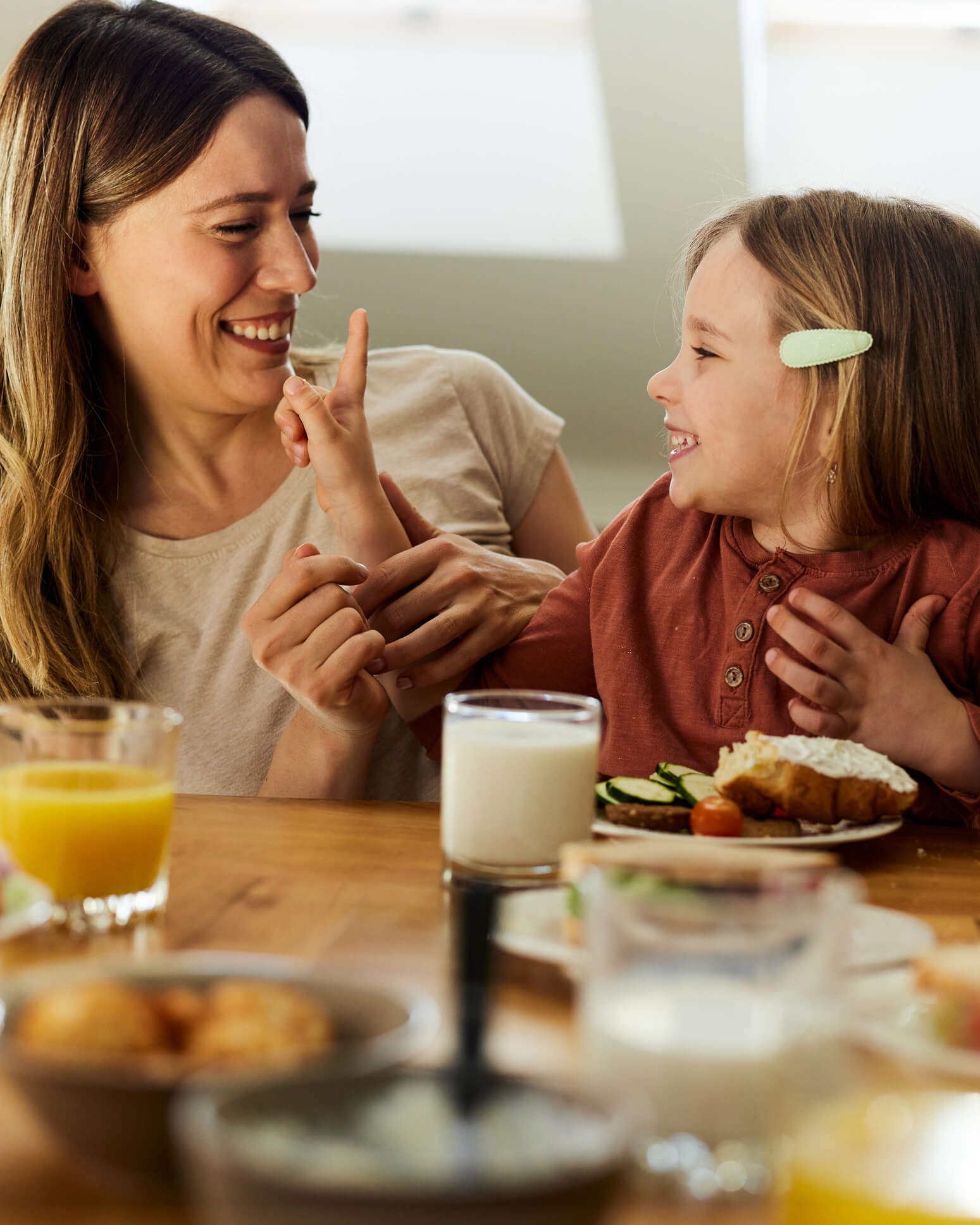 Adult and Child having a breakfast meal at table, being playful, and smiling.