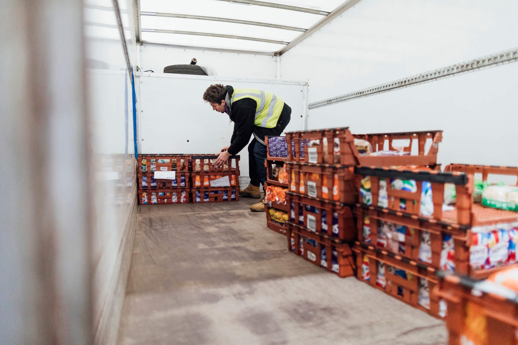 volunteer organizing food items in baskets in food bank box truck