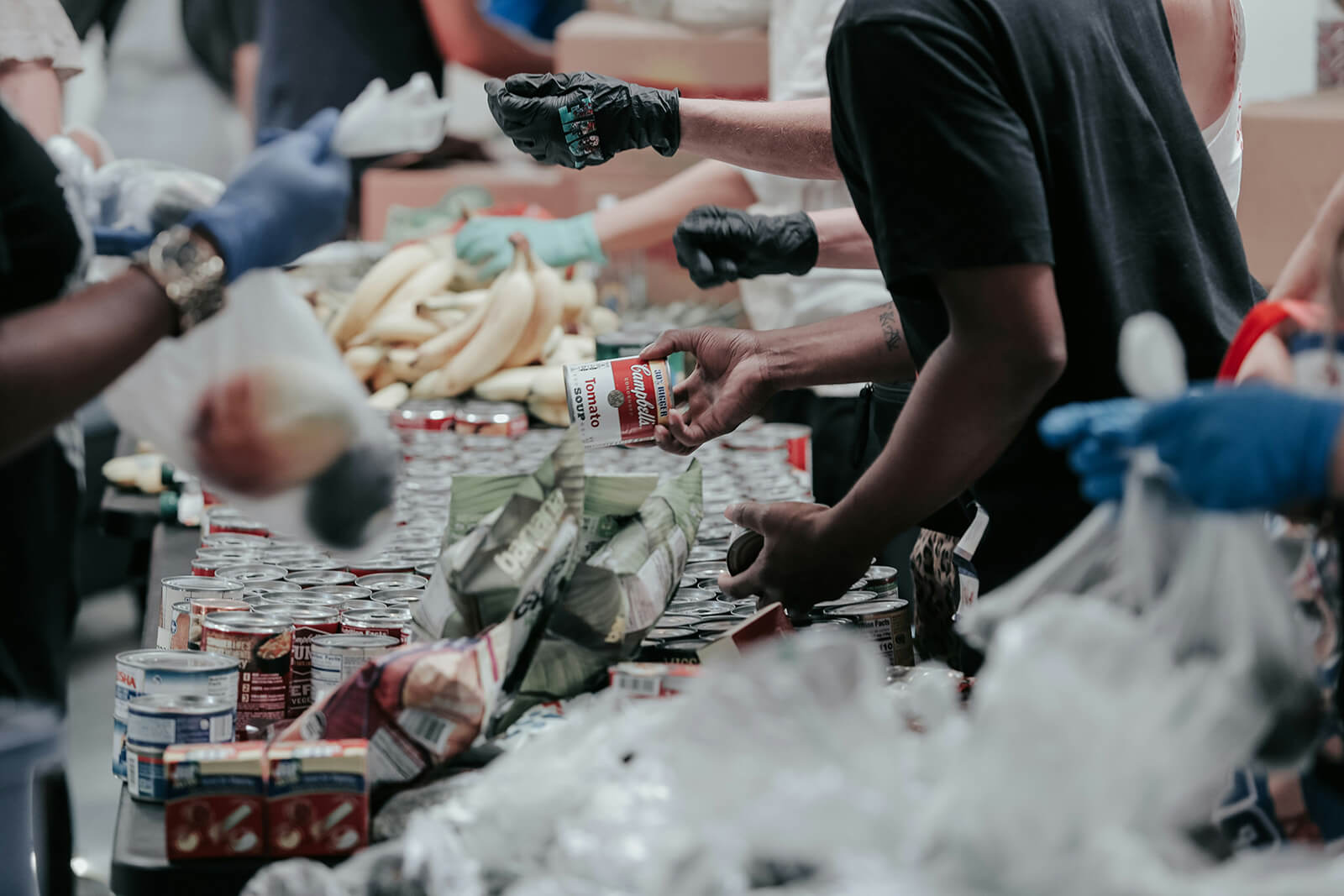 food bank with people coming to take the food they need and interacting with volunteers